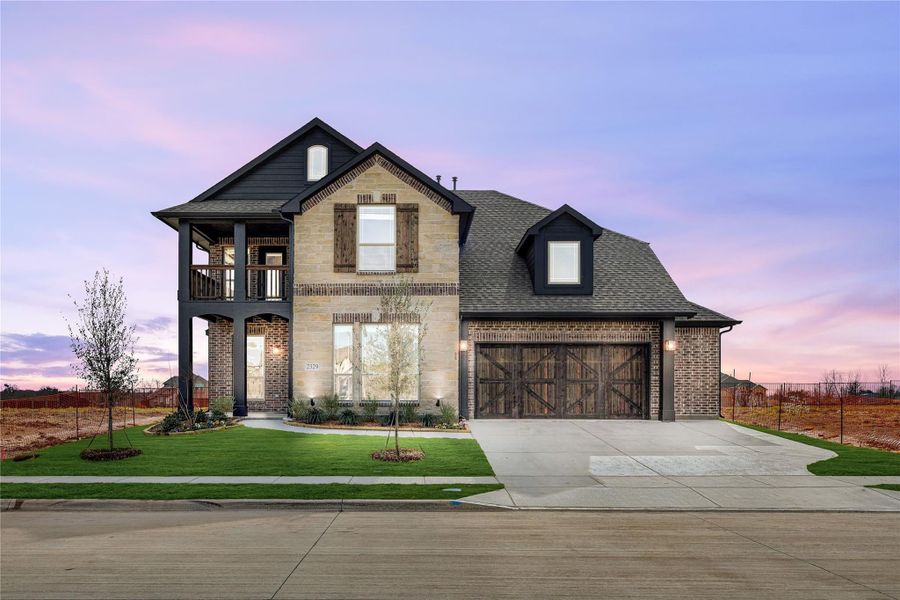 Two-story home with stone and brick exterior, wood garage doors, and second-floor balcony Two-story home with stone and brick exterior, wood garage doors, and second-floor balcony