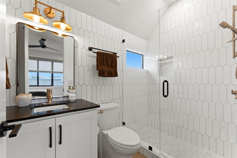 Contemporary bathroom featuring a glass-enclosed shower with white elongated hexagonal tile walls and a pebble-finish shower floor Contemporary bathroom featuring a glass-enclosed shower with white elongated hexagonal tile walls and a pebble-finish shower floor