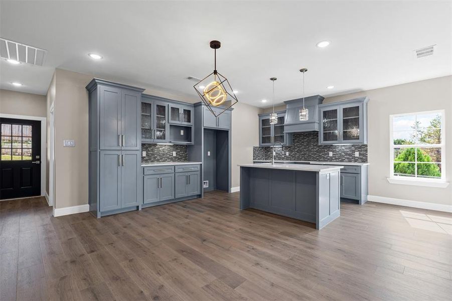 Kitchen featuring glass insert cabinets, plenty of natural light, gray cabinetry, and recessed lighting Kitchen featuring glass insert cabinets, plenty of natural light, gray cabinetry, and recessed lighting