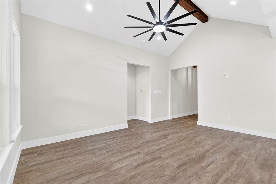Kitchen featuring a large island with a white countertop, two-tone cabinetry, stainless steel microwave, black gas range, and wood-finish flooring