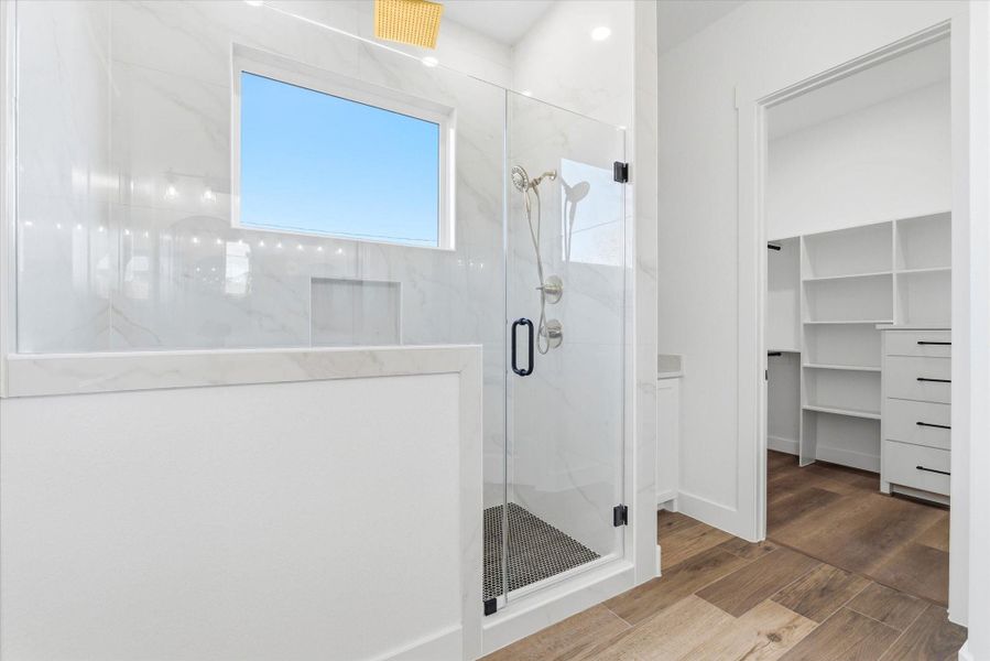A stunning glass-enclosed walk-in shower features multiple shower heads for a spa-like experience.