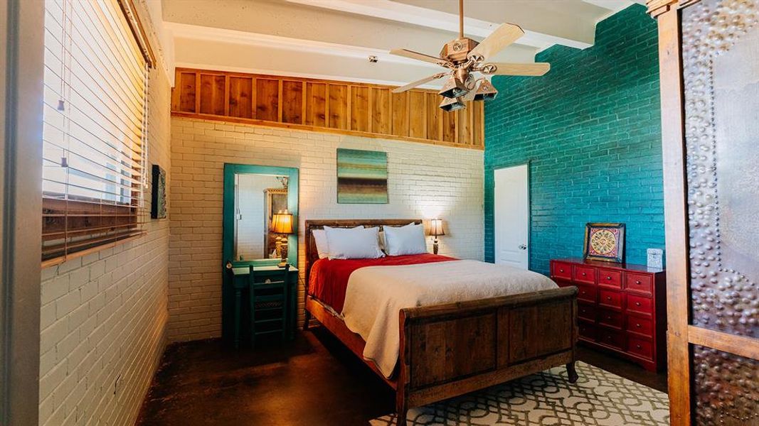 Bedroom with beamed ceiling, a ceiling fan, and finished concrete floors