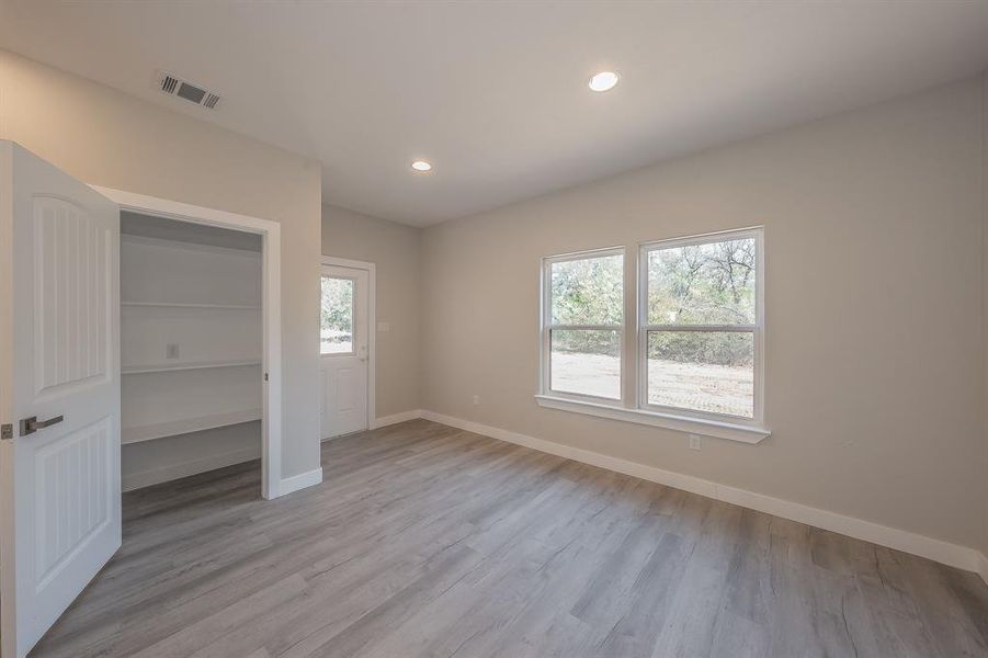 Unfurnished bedroom with light wood finished floors, multiple windows, and recessed lighting