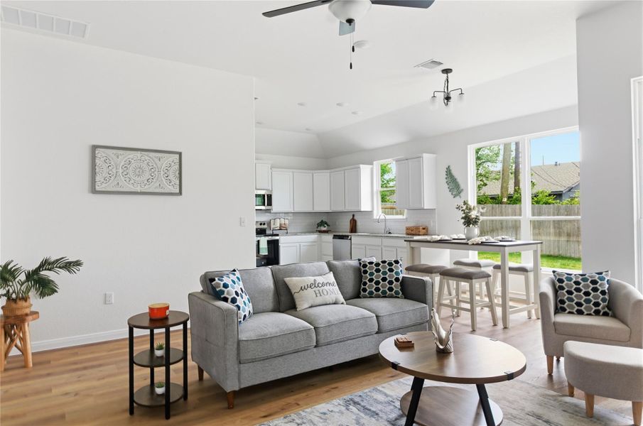 Living room featuring light wood-type flooring, ceiling fan, and lofted ceiling