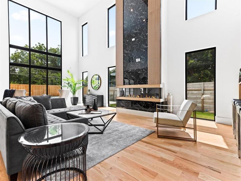 Living room with a high ceiling, light hardwood / wood-style floors, and a fireplace