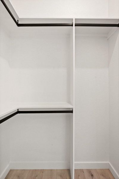 This closet features white walls, built-in shelving, and black hanging rods