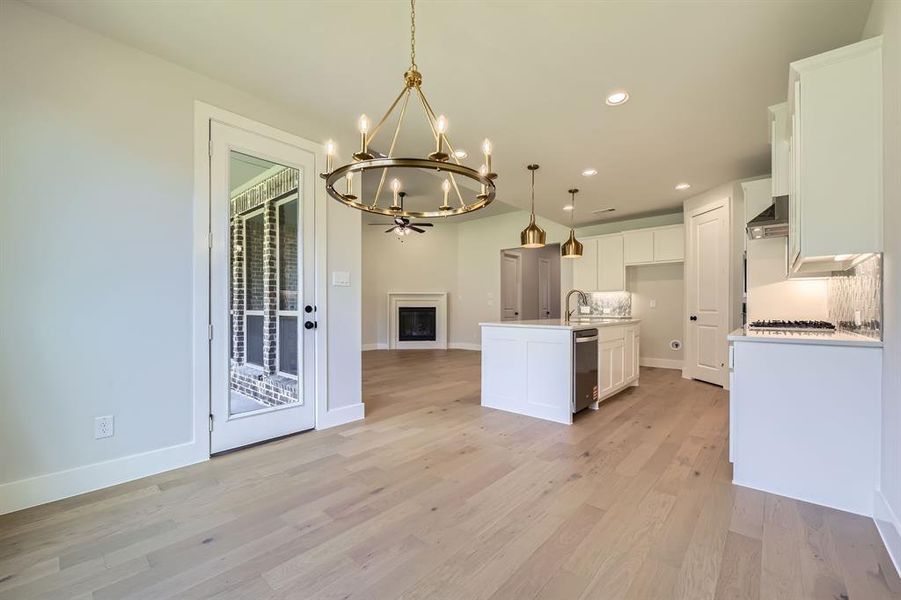 Kitchen featuring a chandelier, white cabinetry, recessed lighting, open floor plan, and light wood-style flooring Kitchen featuring a chandelier, white cabinetry, recessed lighting, open floor plan, and light wood-style flooring