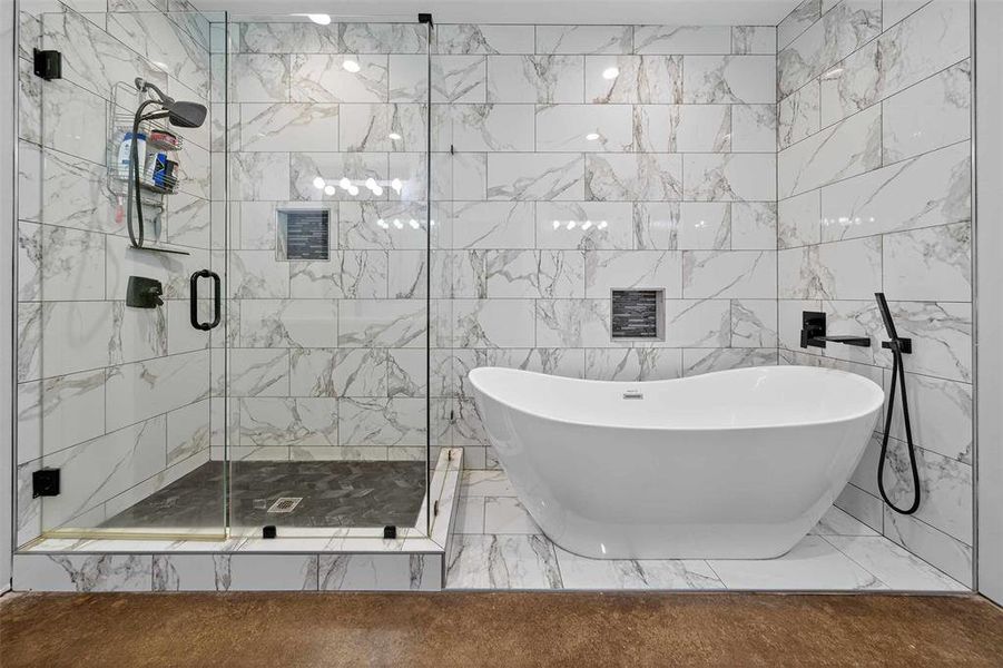 Full bathroom featuring a soaking tub, a stall shower, tile walls, and marble finish floors Full bathroom featuring a soaking tub, a stall shower, tile walls, and marble finish floors
