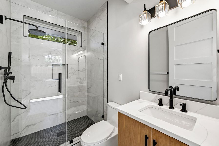 1st Floor Bathroom featuring a spacious walk in shower. (This is Unit #2 - each Unit has the same layout, however a few differing details such as light fixtures, custom cabinet/backsplash/tile colors)