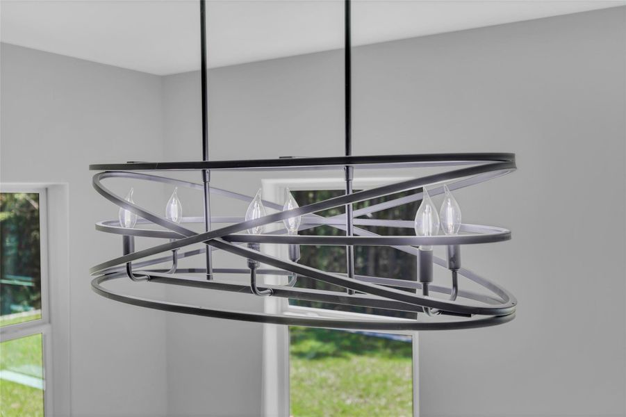Modern chandelier with a sleek, geometric design featuring multiple light bulbs. It hangs in a bright room with large windows, offering a view of green outdoor scenery. Modern chandelier with a sleek, geometric design featuring multiple light bulbs. It hangs in a bright room with large windows, offering a view of green outdoor scenery.