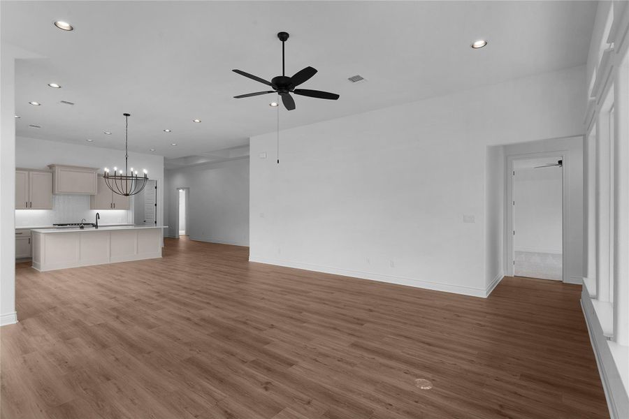 Unfurnished living room with a chandelier, a ceiling fan, and light wood-style flooring