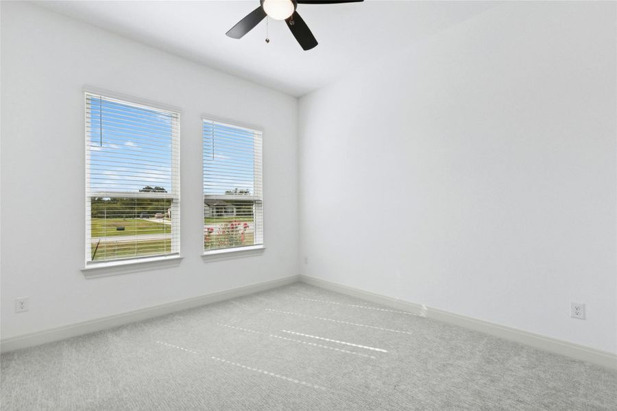 Carpeted spare room with baseboards and a ceiling fan Carpeted spare room with baseboards and a ceiling fan