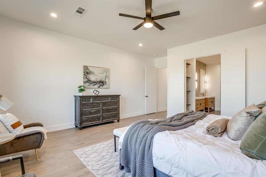 Bedroom with recessed lighting, light wood-style flooring, ceiling fan, ensuite bathroom, and a walk in closet Bedroom with recessed lighting, light wood-style flooring, ceiling fan, ensuite bathroom, and a walk in closet