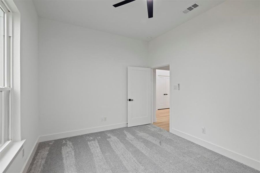 Carpeted spare room featuring a ceiling fan and baseboards