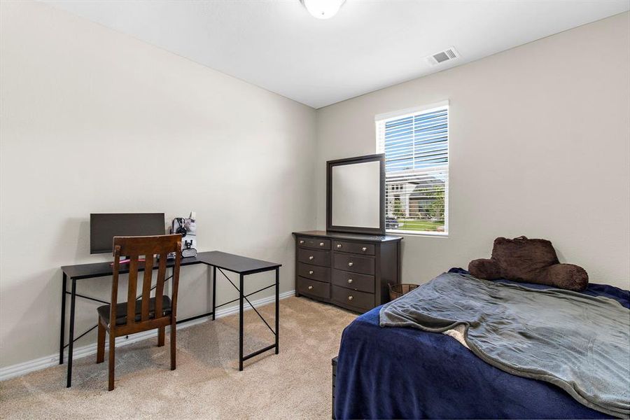 Carpeted bedroom featuring baseboards and a desk Carpeted bedroom featuring baseboards and a desk