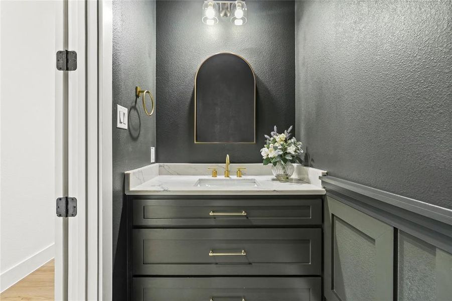 Bathroom featuring a textured wall, vanity, and wood finished floors Bathroom featuring a textured wall, vanity, and wood finished floors