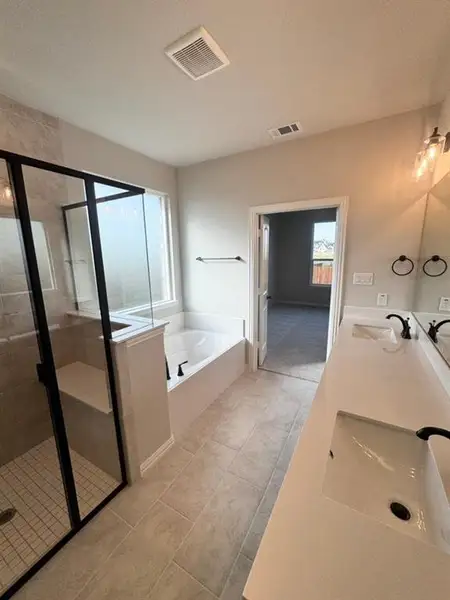 Spacious bathroom featuring a glass-enclosed shower with a built-in bench, a separate soaking tub, and a double vanity with integrated sinks