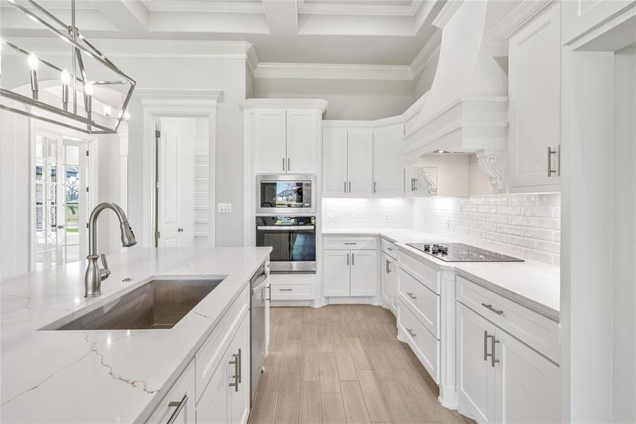 Kitchen featuring appliances with stainless steel finishes, white cabinetry, decorative backsplash, pendant lighting, and light stone countertops Kitchen featuring appliances with stainless steel finishes, white cabinetry, decorative backsplash, pendant lighting, and light stone countertops