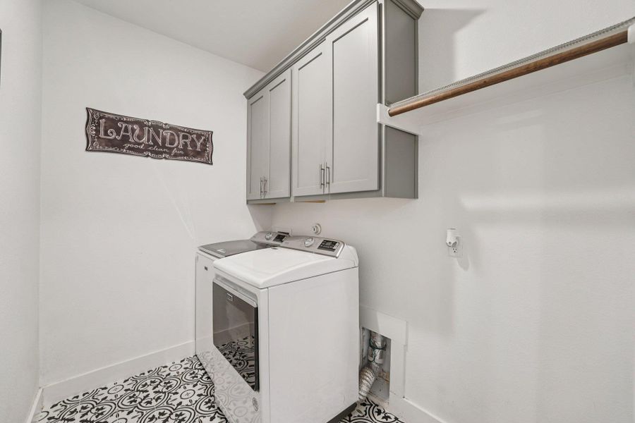 Well-appointed laundry room with built-in cabinetry, hanging space, and stylish flooring designed for everyday function and easy maintenance.