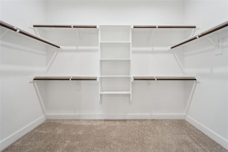 Spacious primary closet with light colored carpet