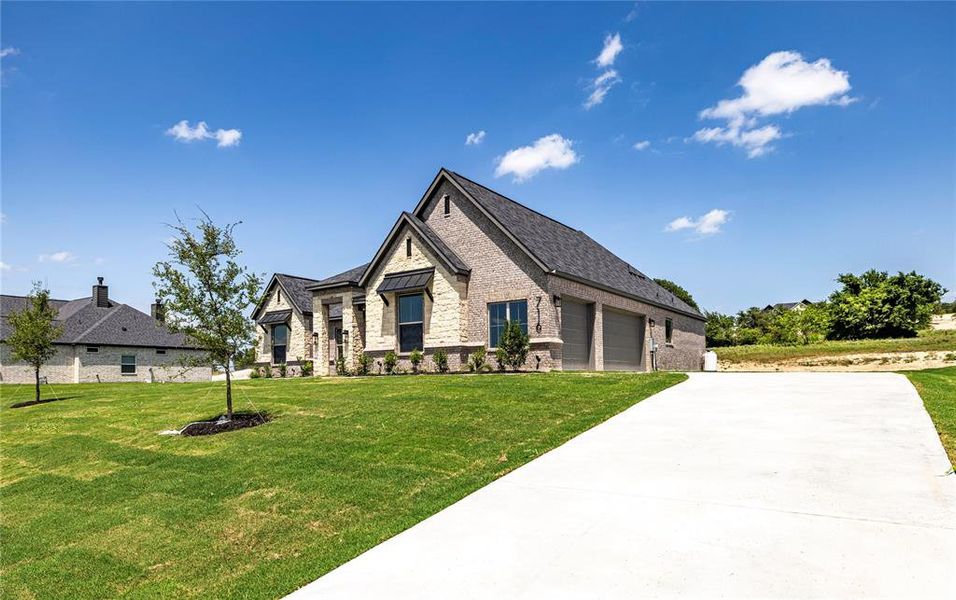 French country home featuring driveway, a front lawn, a garage, and brick siding French country home featuring driveway, a front lawn, a garage, and brick siding