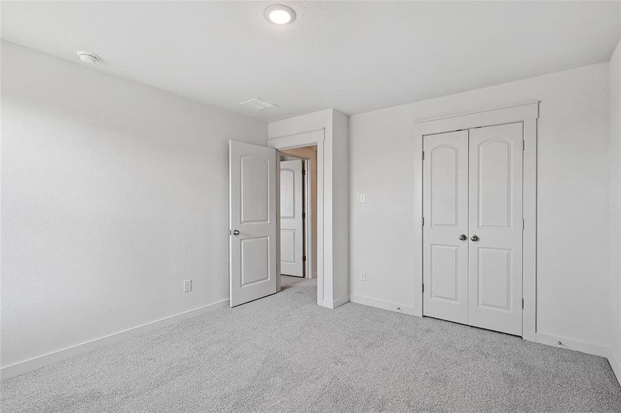 Unfurnished bedroom with light colored carpet and a closet