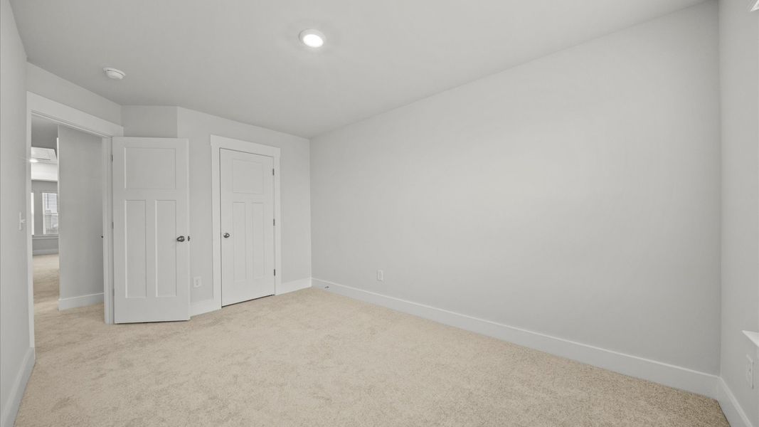 Bright and serene bedroom with comfortable carpeted flooring and large windows for vibrant light