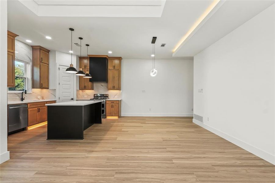 Kitchen with decorative light fixtures, a center island, appliances with stainless steel finishes, light wood-style flooring, and recessed lighting
