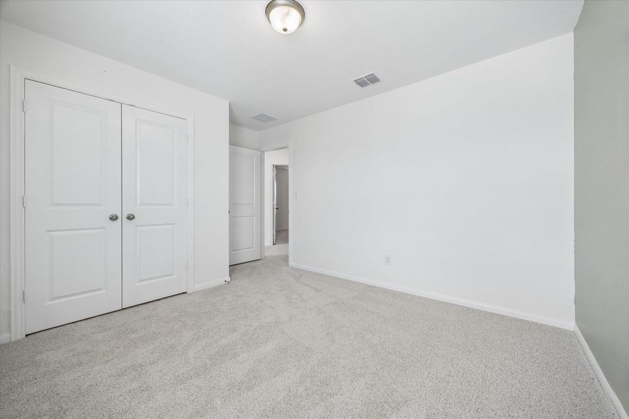Unfurnished bedroom with light carpet and a closet