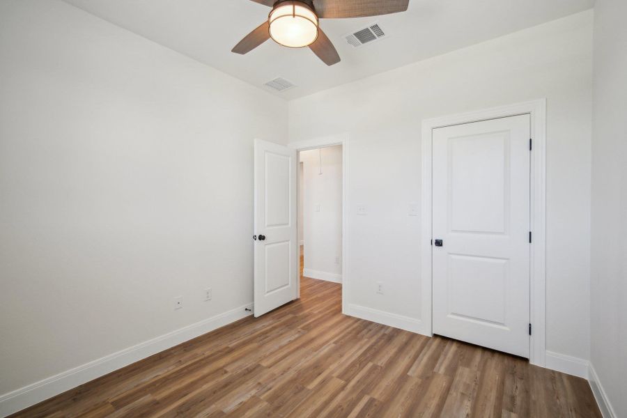 Bedroom 4 featuring wood finished floors, baseboards, ceiling fan, and visible vents Bedroom 4 featuring wood finished floors, baseboards, ceiling fan, and visible vents