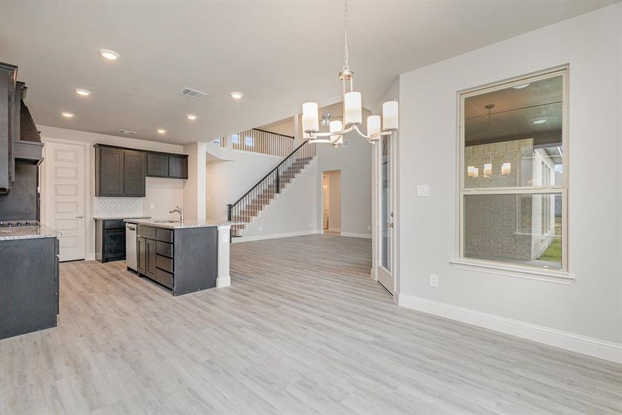 Kitchen with dark brown cabinets, sink, light hardwood / wood-style flooring, an inviting chandelier, and hanging light fixtures