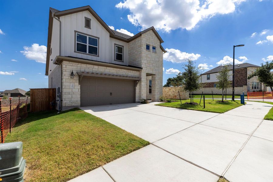 View of front of house with board and batten siding, a garage, stone siding, and concrete driveway