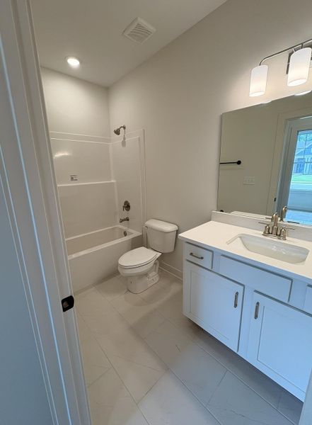 Bathroom with white tub/shower combination, white toilet, and white vanity with an undermount sink