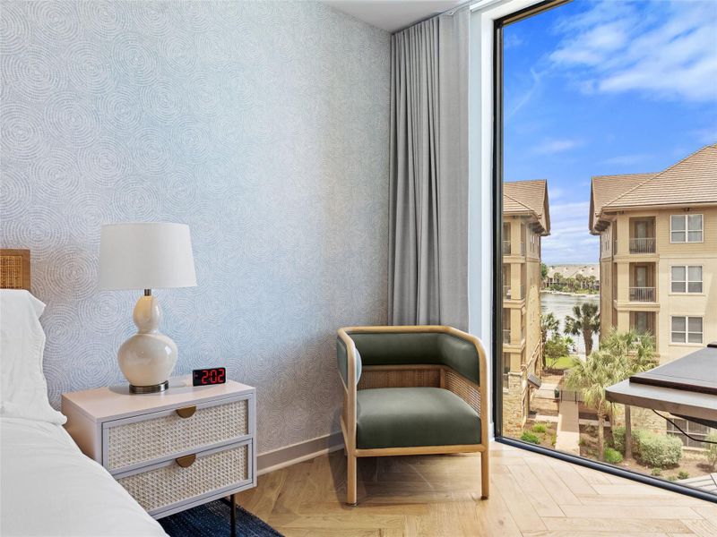 Floor-to-ceiling window offering outdoor scenery, wood-finish flooring, patterned accent wall, and drapery Floor-to-ceiling window offering outdoor scenery, wood-finish flooring, patterned accent wall, and drapery