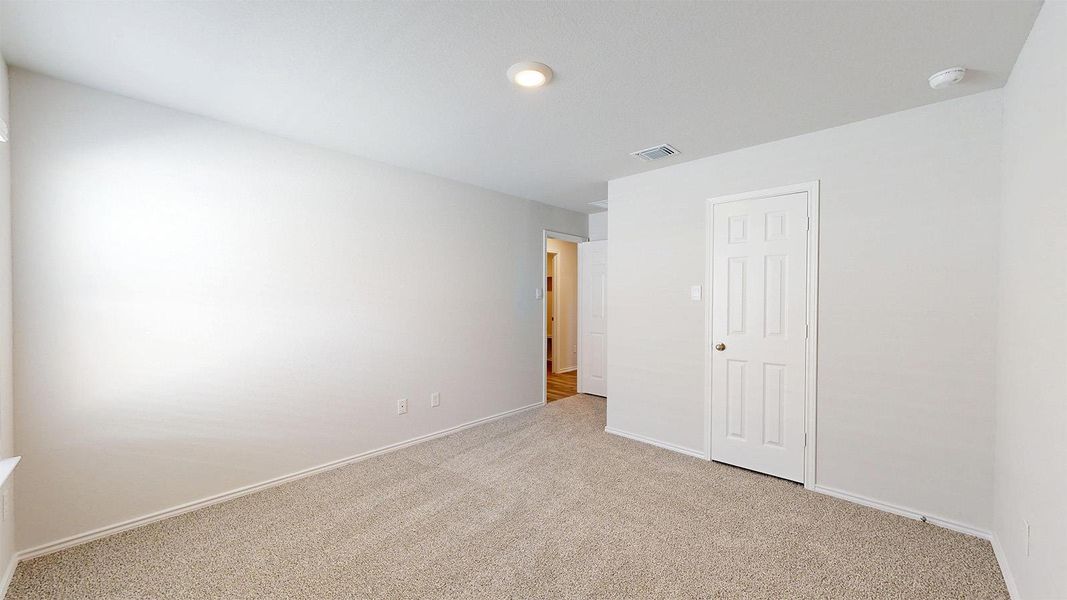 Unfurnished bedroom with light colored carpet and baseboards