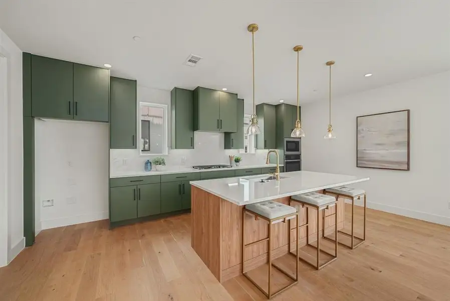 Contemporary kitchen featuring olive green cabinetry, light wood-finish flooring, and a large center island with seating Contemporary kitchen featuring olive green cabinetry, light wood-finish flooring, and a large center island with seating