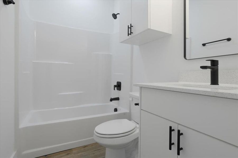 Full bathroom featuring bathtub / shower combination, hardwood / wood-style floors, vanity, and toilet