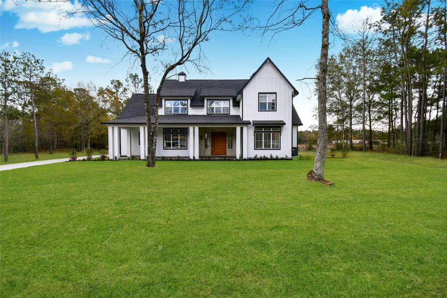 Architectural perfection featuring crisp white board-and-batten siding, bold black window accents, and a custom wood-stained entry door. The expansive green lawn offers incredible curb appeal.