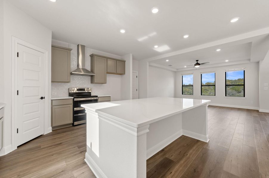Spacious kitchen featuring built in microwave drawer, large center island, abundant storage, breakfast bar, eat-in kitchen dining area, modern style range hood, stainless appliances, and pantry
