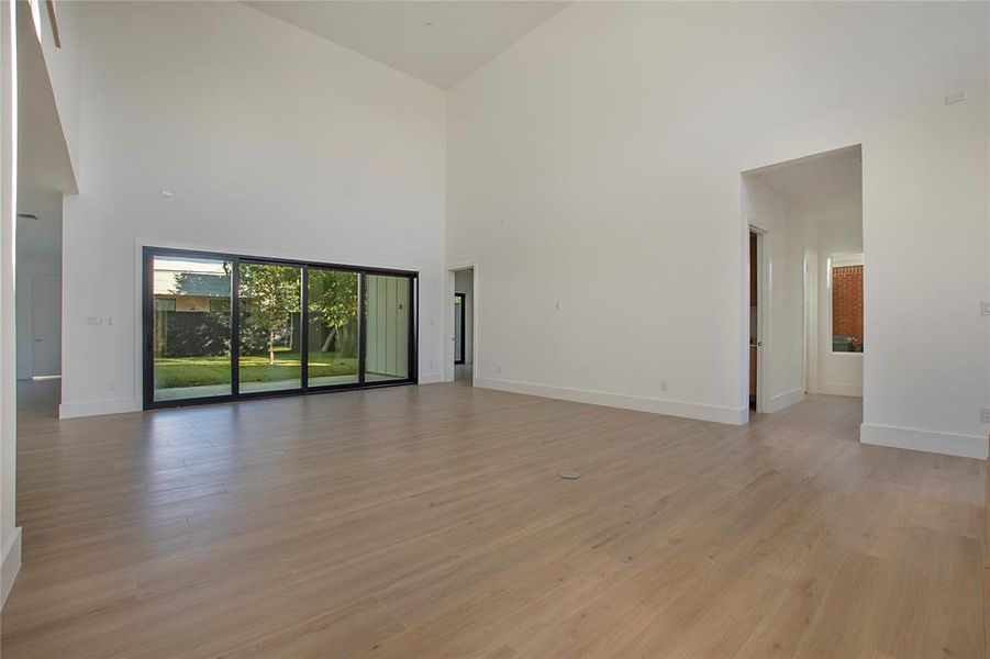 Unfurnished living room featuring light hardwood / wood-style flooring and high vaulted ceiling