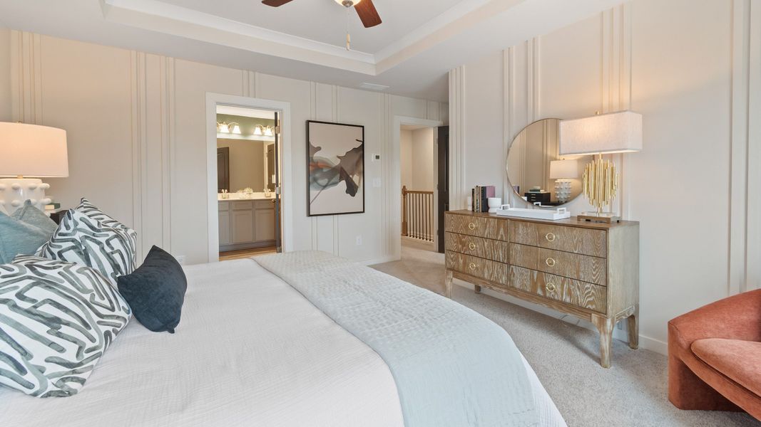 Primary Bedroom with tray ceiling, accent walls, carpet, ceiling fan, and windows