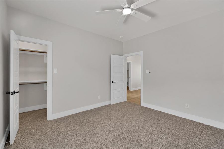 Unfurnished bedroom featuring carpet, baseboards, ceiling fan, a closet, and a spacious closet Unfurnished bedroom featuring carpet, baseboards, ceiling fan, a closet, and a spacious closet