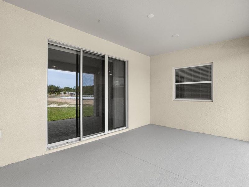 A triple sliding glass door opens to outdoor living space on your covered lanai - Everly by Highland Homes