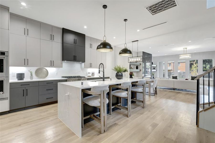 Kitchen featuring an island with sink, sink, gray cabinets, and a kitchen breakfast bar