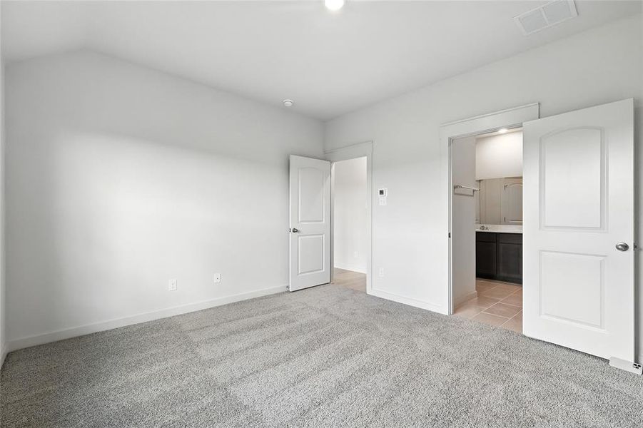 Unfurnished bedroom featuring light colored carpet, connected bathroom, and light tile patterned flooring Unfurnished bedroom featuring light colored carpet, connected bathroom, and light tile patterned flooring