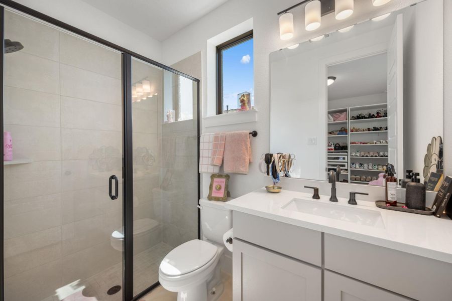 A well-lit bathroom features a spacious shower with sleek black framing and a contemporary vanity with a large mirror. A well-lit bathroom features a spacious shower with sleek black framing and a contemporary vanity with a large mirror.