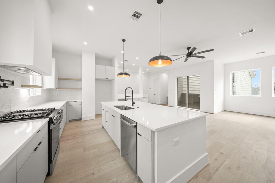 Imagine preparing your favorite meals & recipes while your guests mingle about the kitchen island and nearby living spaces. The open layout flows into the living space with natural light from large windows, creating a welcoming environment that’s both functional and visually connected.
