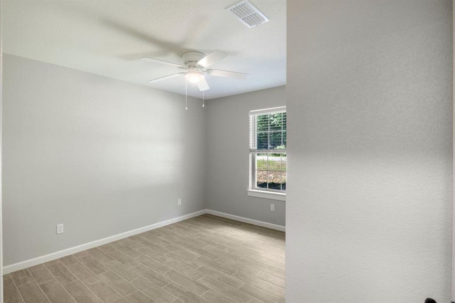 Empty room with wood tiled floors and a ceiling fan Empty room with wood tiled floors and a ceiling fan