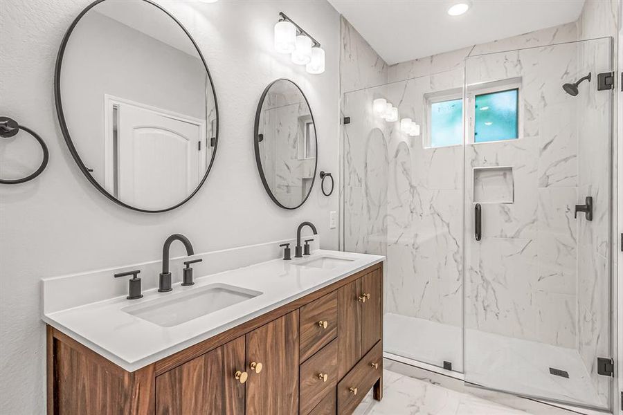 Double vanity in the primary bath with seamless glass shower enclosure.