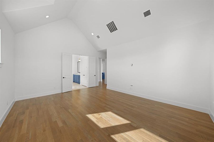 Unfurnished bedroom featuring high vaulted ceiling and wood finished floors Unfurnished bedroom featuring high vaulted ceiling and wood finished floors